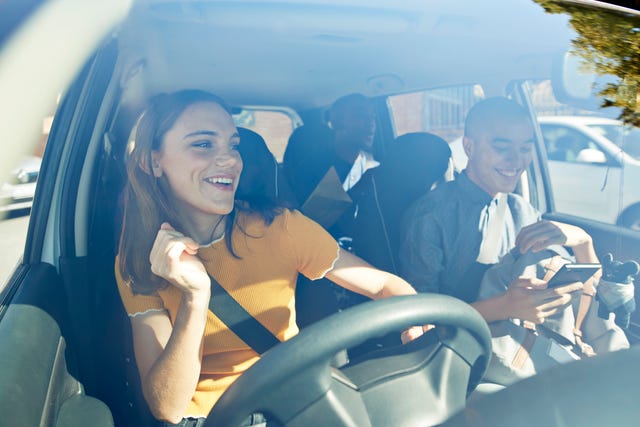 happy young woman dancing with friends in car