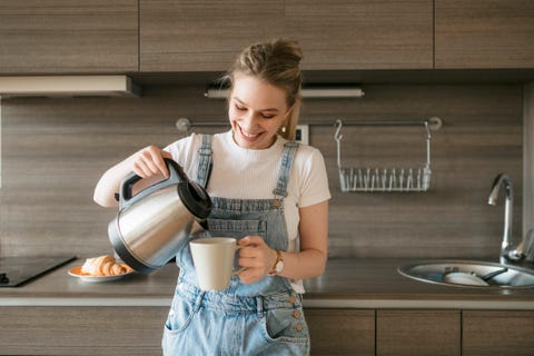 Happy young woman pouring herself some morning coffee happy young woman pouring herself some morning coffee