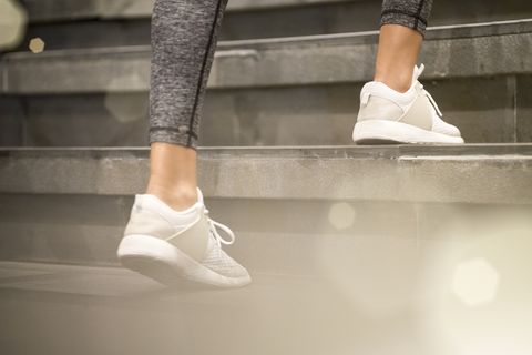 Close up of female legs with white sport sneakers running up the stairs