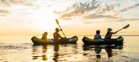 Los cinco deportes acuáticos más eficaces Having Fun Sea Kayaking At Sunset