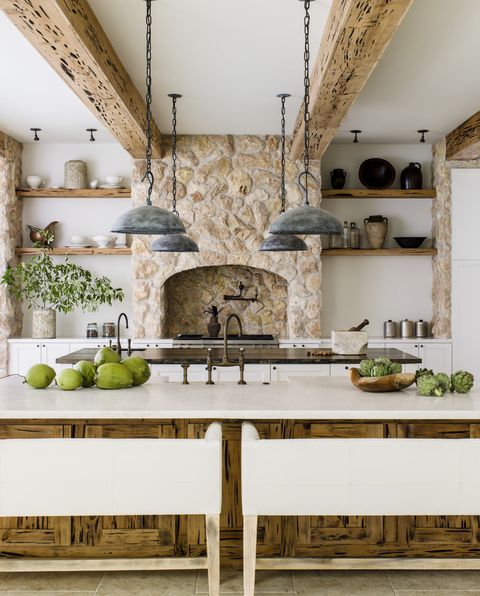 kitchen
symmetrical open shelving
and repetitive light
fixtures put the focus on
the jerusalem stone–clad,
chimney style range hood
pendants the urban electric
co seating verellen
paint snow white,
benjamin moore counter
coral stone island and
beams pecky cypress