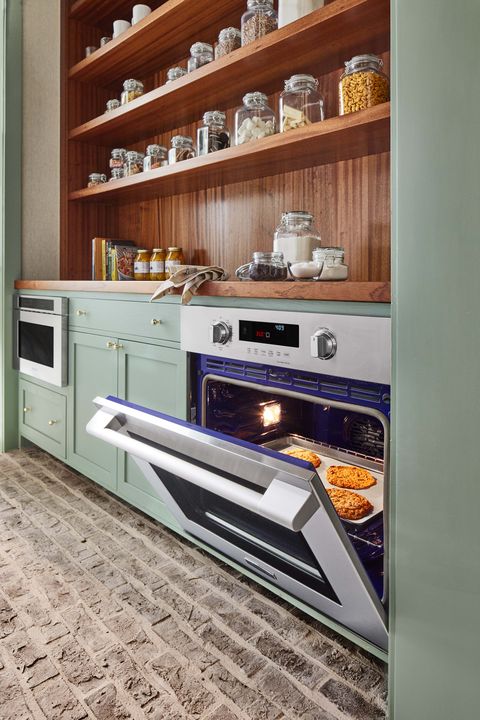 cozinha, armários verdes, forno, placa de madeira e prateleiras de madeira