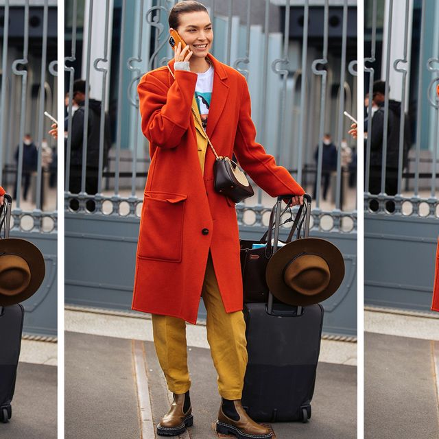 a model stands with a suitcase and bags to illustrate a guide to the best garment bags 2022
