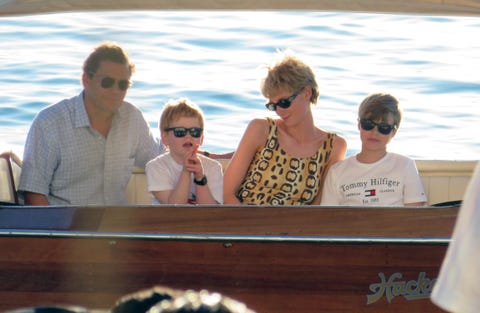 actors who play princess diana, prince charles, and william and harry sit in a boat