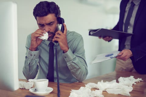 Zieke man op werk met telefoon in zijn hand