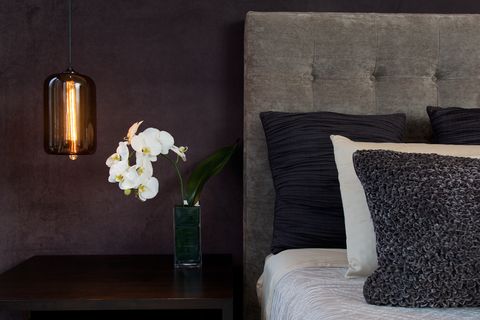 headboard detail with pillows lamp and orchid flowers