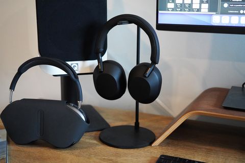 two headphones in headphone stands on a desk