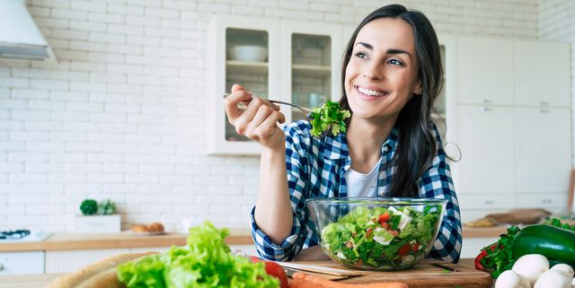 healthy lifestyle good life organic food vegetables close up portrait of happy cute beautiful young woman while she try tasty vegan salad in the kitchen at home