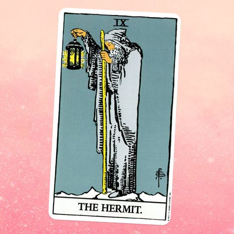 the hermit tarot card, showing an old man with a beard and a gray robe holding a wooden staff and a lantern
