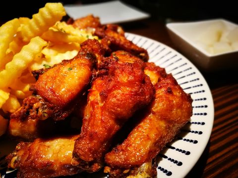 High Angle Close-Up Of Chicken Wings In Plate On Wooden Table