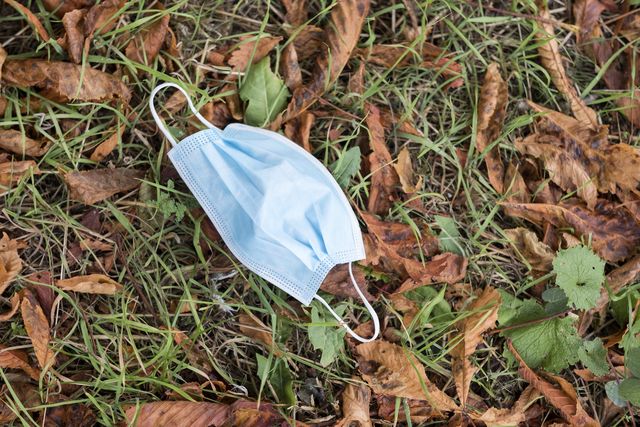 high angle close up of disposed blue surgical face mask lying on ground