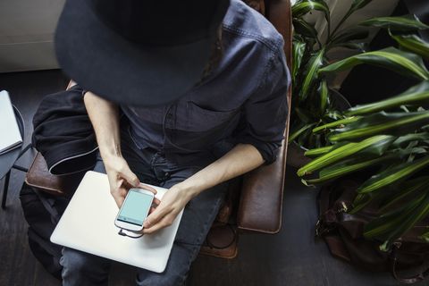 High angle view of blogger using phone while sitting on chair
