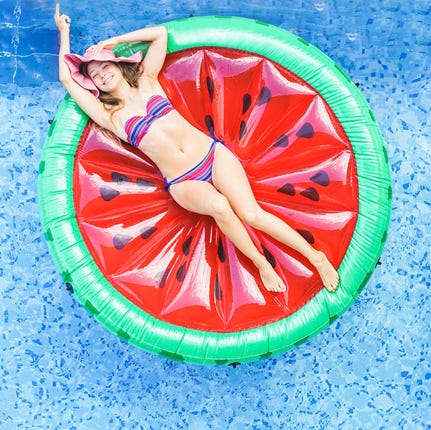 High Angle View Of Female Friends Relaxing On Inflatable Rings In Swimming Pool High Angle View Of Female Friends Relaxing On Inflatable Rings In Swimming Pool