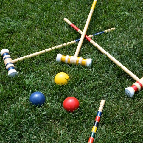 high angle view of multi colored croquet balls and mallets on grass lawn