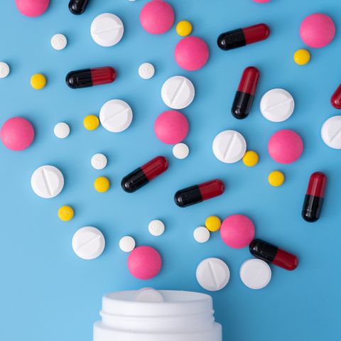 high angle view of pills spilling form bottle on blue background