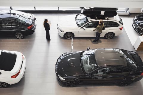 high angle view of saleswoman and customer looking at car in showroom