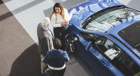 High angle view of saleswoman showing car to customers at showroom