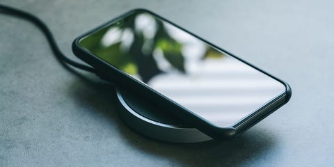 High Angle View Of Smart Phone Getting Charged On Table