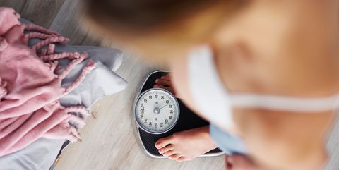High Angle View Of Woman Standing On Weight Scale At Home