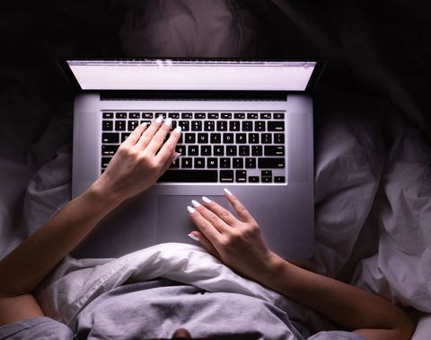 high angle view of woman using laptop while sitting on bed