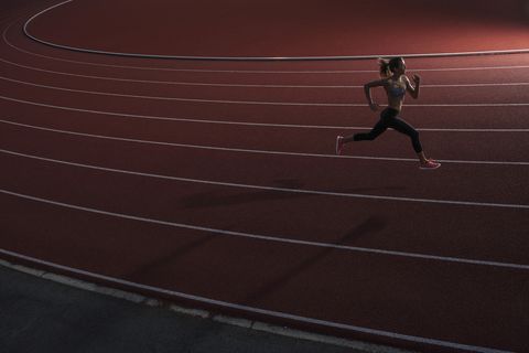 High angle view of young female athlete running on race track