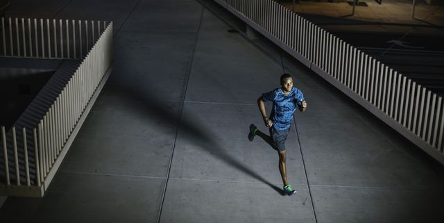 high angle view of young man running on city walkway at night