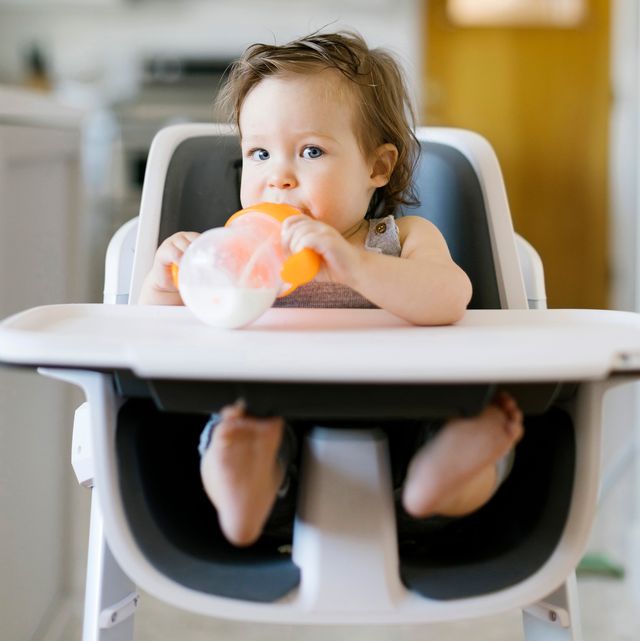 baby with sippy cup sitting in high chair
