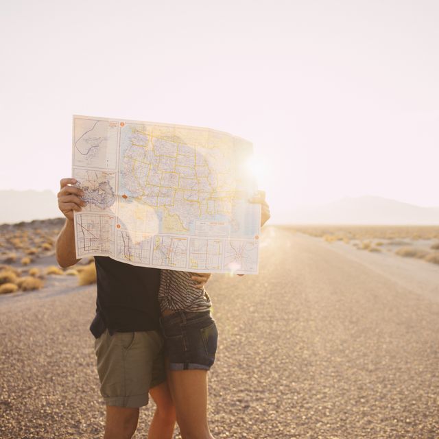 hispanic couple kissing behind map on remote road