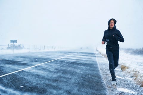 Hispanic woman jogging on snow covered road