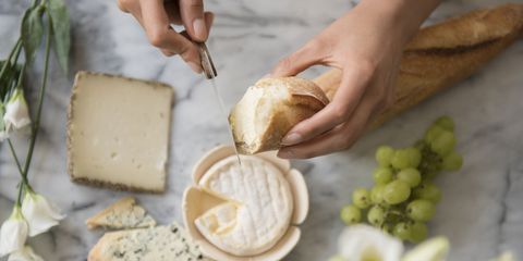 Hispanic woman spreading cheese on bread