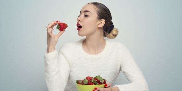 hispanic woman young woman eats fresh strawberries