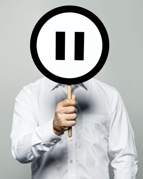 man holding pause sign in front of face