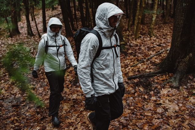 two people walking in the woods wearing rain coats