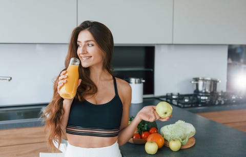 Holds apple in hand. Young european woman is indoors at kitchen indoors with healthy food holds apple in hand young european woman is indoors at kitchen indoors with healthy food
