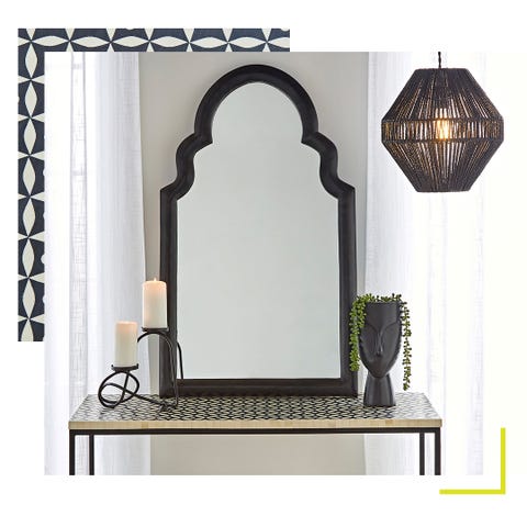 mirror sitting on a patterned sideboard, alongside a plant pot and candle