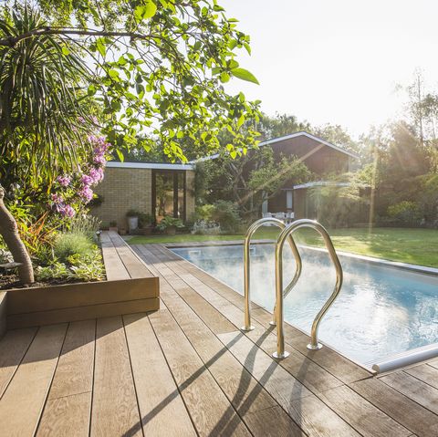 sunbeams over idyllic home showcase swimming pool in summer backyard