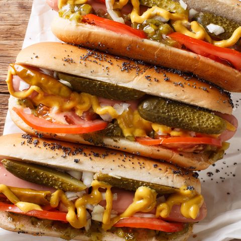 Homemade Chicago style hot dogs with mustard, tomatoes, pickled cucumbers, onions and relish close-up. Horizontal top view