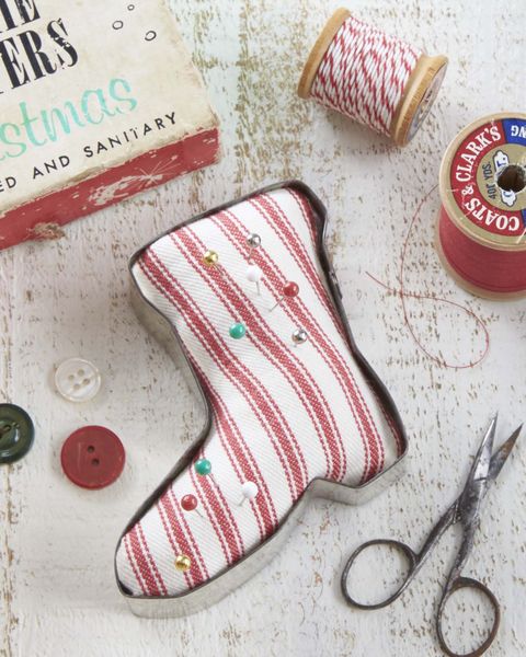 a vintage santa boot shaped cookied cutter turned into a pin cushion using red and white ticking striped fabric