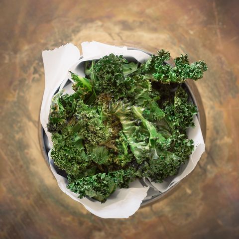 homemade crispy kale chips with parchment paper in a bowl