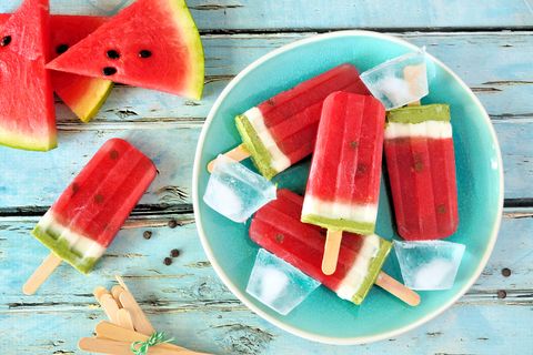Homemade summer watermelon popsicles on a plate, top view over rustic blue wood