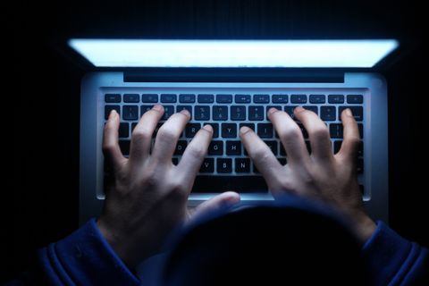 hooded cyber hacker working on laptop