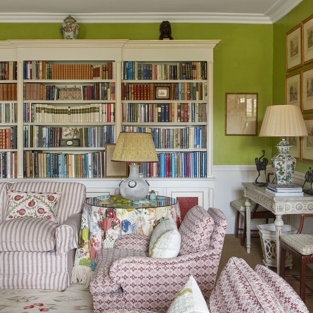 a table skirt made from old colefax and fowler sample books in a drawing room with book shelves and comfy chairs