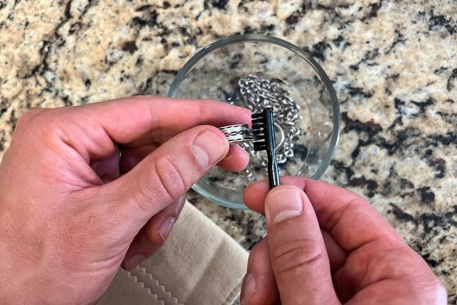 person cleaning silver jewelry with a soft bristle brush