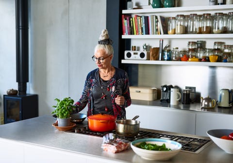woman in her 60s with glasses preparing food in stylish kitchen, organisation, preparation, skill