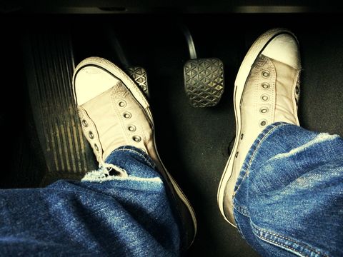 Human foot with brake and gas pedals in car