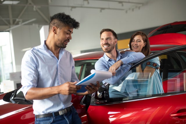 husband and wife buying a new car together at a car dealership salon