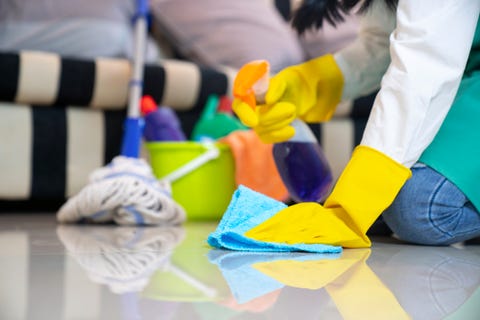 husband housekeeping and cleaning concept, happy young  woman in blue rubber gloves wiping dust using a spray and a duster while cleaning on floor at home