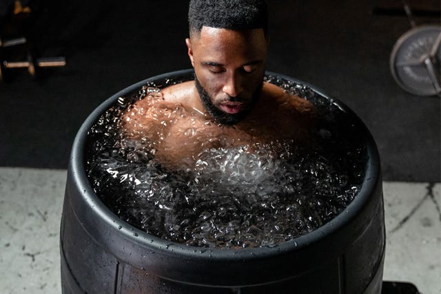 a man taking an ice bath in a barrel
