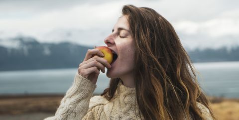 Iceland, woman eating an apple at lakeside