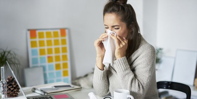 ill woman at home at desk blowing her nose